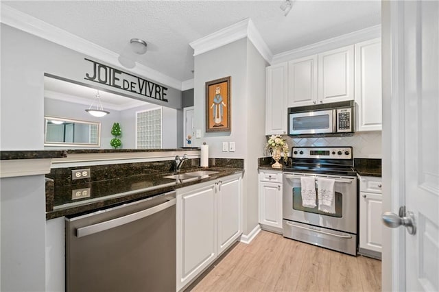 kitchen with white cabinets, sink, light hardwood / wood-style flooring, ornamental molding, and appliances with stainless steel finishes