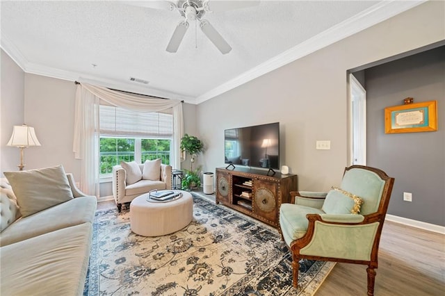 living room with a textured ceiling, ceiling fan, wood-type flooring, and ornamental molding