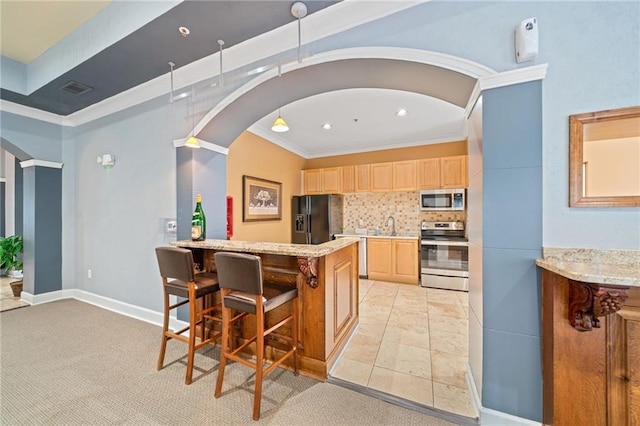 kitchen featuring a kitchen bar, appliances with stainless steel finishes, backsplash, ornamental molding, and light brown cabinets