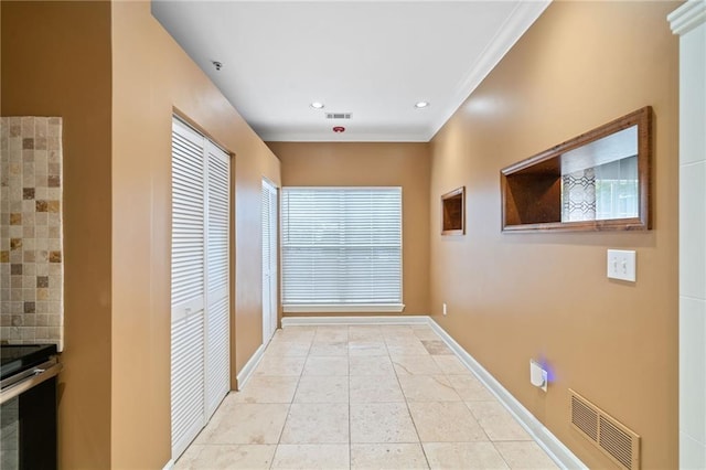 hallway with light tile patterned floors and crown molding