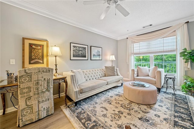 living room with ceiling fan, hardwood / wood-style floors, a textured ceiling, and ornamental molding