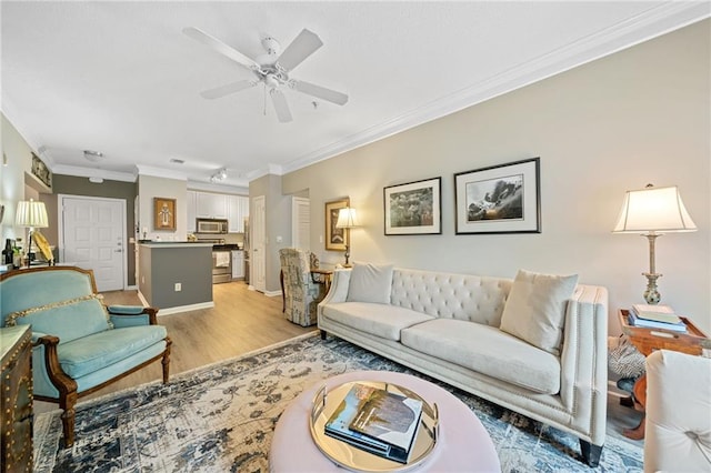 living room with ceiling fan, ornamental molding, and light wood-type flooring