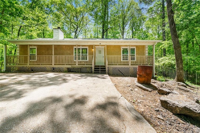 ranch-style house with a chimney and a porch