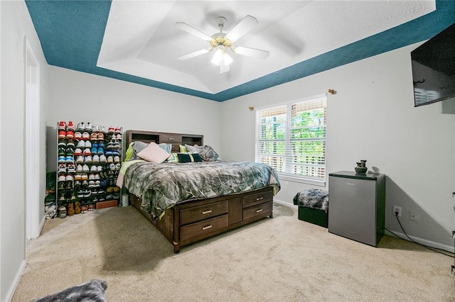 bedroom featuring a tray ceiling, carpet floors, and ceiling fan