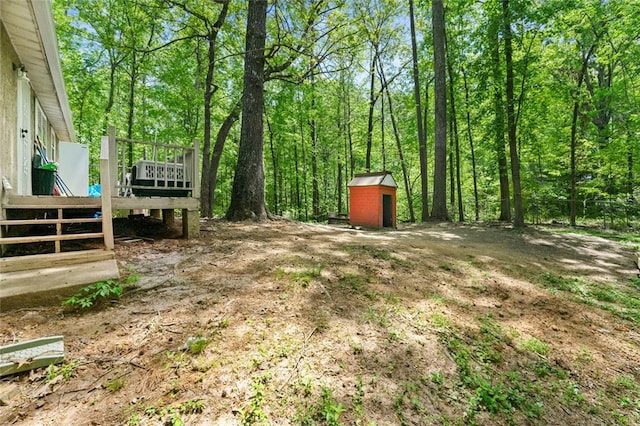 view of yard featuring a wooden deck, a storage shed, and an outdoor structure