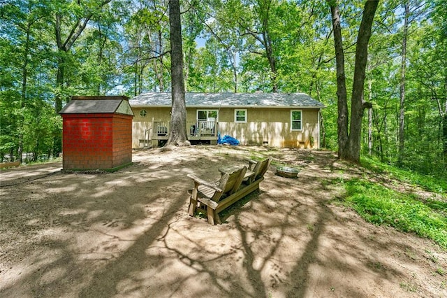 rear view of property featuring an outbuilding, a storage unit, and a deck