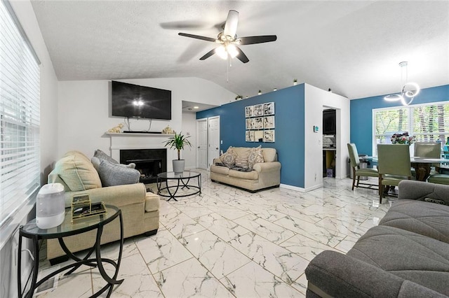 living room with marble finish floor, lofted ceiling, a fireplace, and a ceiling fan