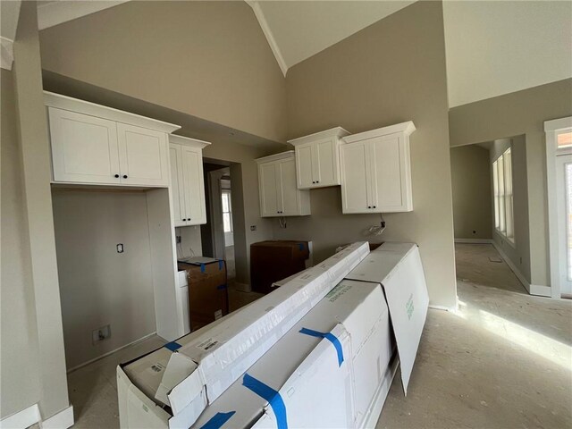 kitchen featuring white cabinetry, high vaulted ceiling, and washing machine and clothes dryer