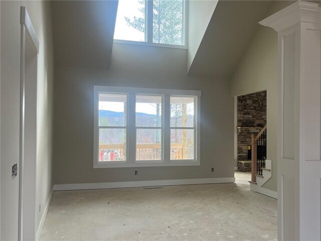 unfurnished room featuring a fireplace and high vaulted ceiling