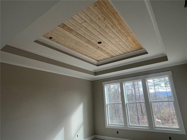 interior details featuring a raised ceiling, wood ceiling, and ornamental molding