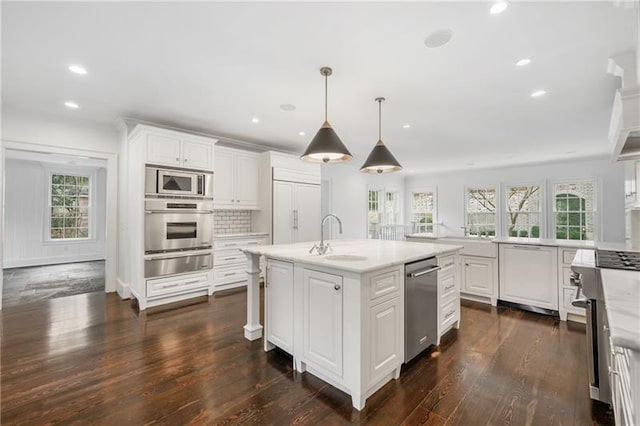 kitchen with white cabinetry, an island with sink, hanging light fixtures, and built in appliances