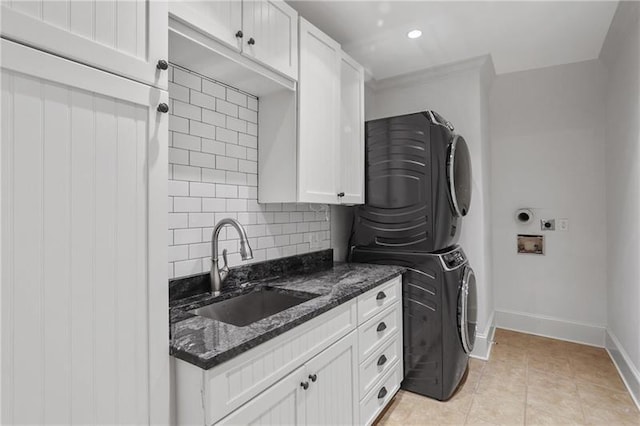 washroom featuring stacked washer / dryer, light tile patterned flooring, sink, and cabinets