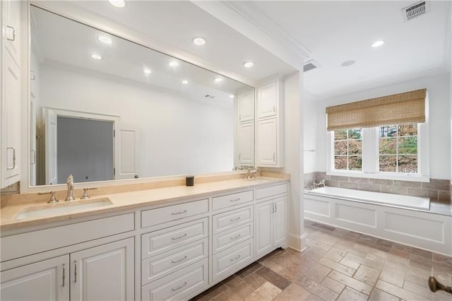 bathroom featuring vanity, ornamental molding, and a tub