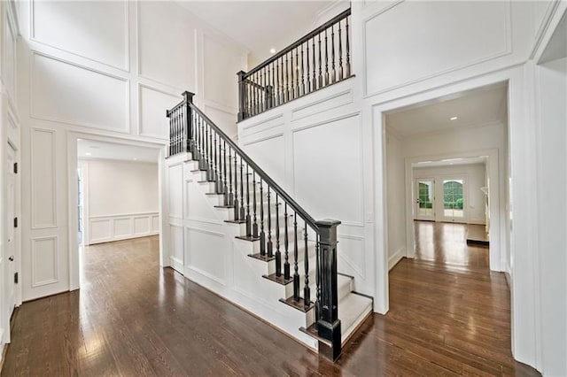 stairs with crown molding, wood-type flooring, and a high ceiling