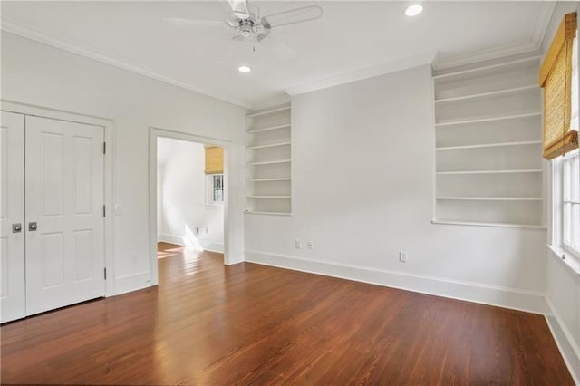 empty room featuring crown molding, hardwood / wood-style floors, built in features, and ceiling fan