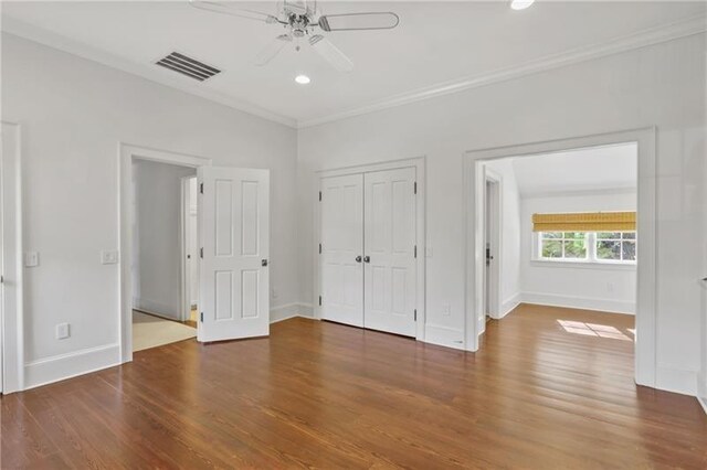 unfurnished bedroom with ornamental molding, ceiling fan, dark hardwood / wood-style flooring, and a closet