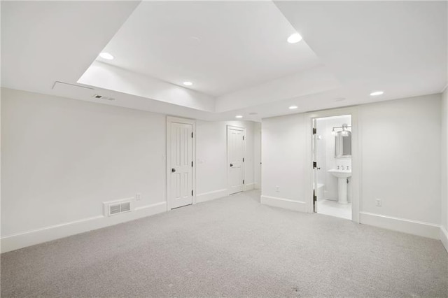 carpeted spare room with sink and a tray ceiling