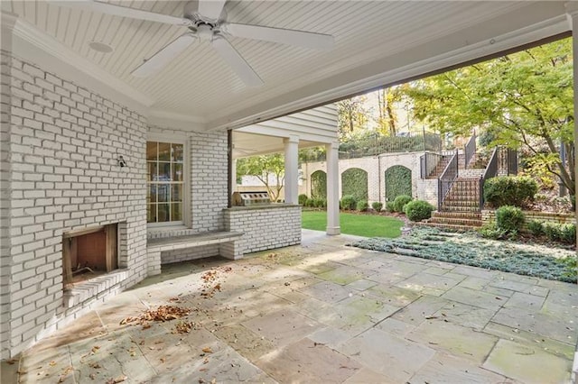 view of patio featuring an outdoor brick fireplace and ceiling fan