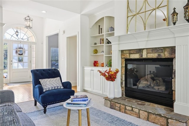 living room with built in shelves, a fireplace, and wood-type flooring