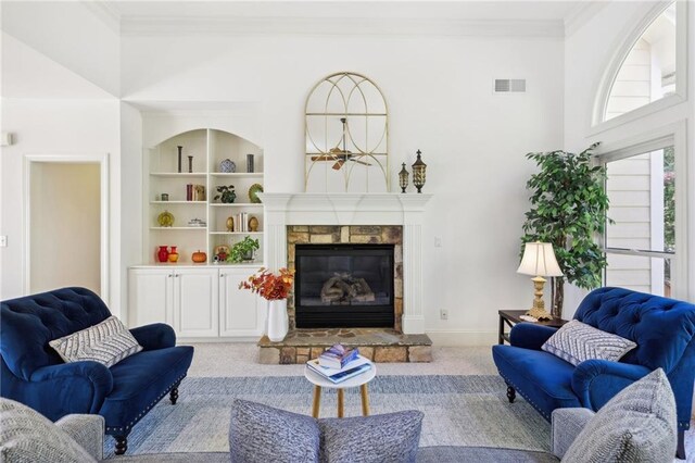 carpeted living room featuring a towering ceiling, ornamental molding, and a fireplace