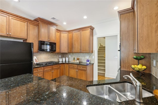 kitchen featuring black appliances, sink, dark stone countertops, crown molding, and decorative backsplash