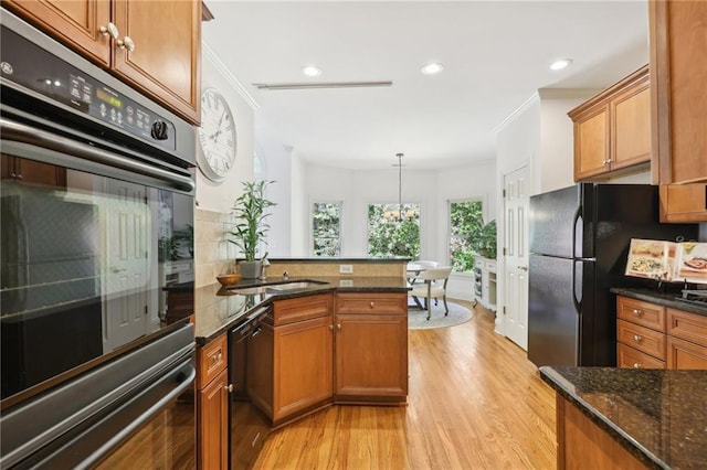 kitchen featuring black appliances, light wood-type flooring, pendant lighting, crown molding, and a chandelier