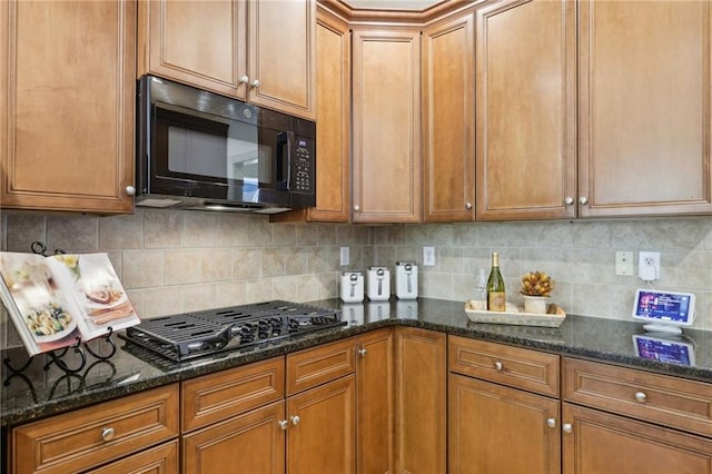 kitchen with black appliances, backsplash, and dark stone counters