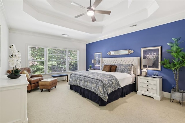 bedroom with ceiling fan, ornamental molding, a tray ceiling, and light colored carpet