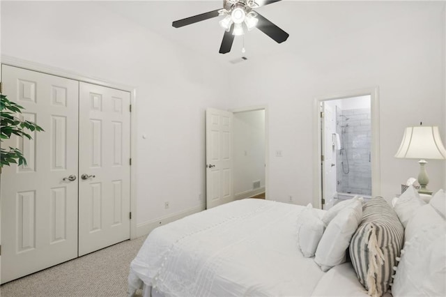 carpeted bedroom featuring a closet, ensuite bath, and ceiling fan