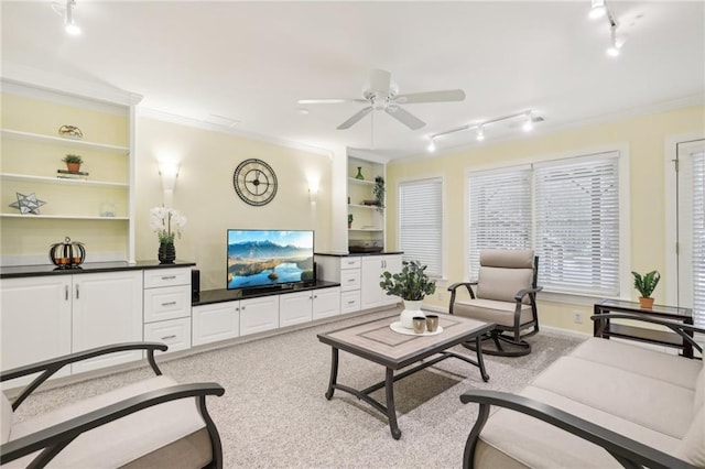 living room featuring built in features, ceiling fan, ornamental molding, track lighting, and light colored carpet