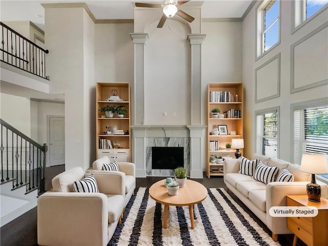 living area with stairway, a fireplace, a towering ceiling, and ornamental molding