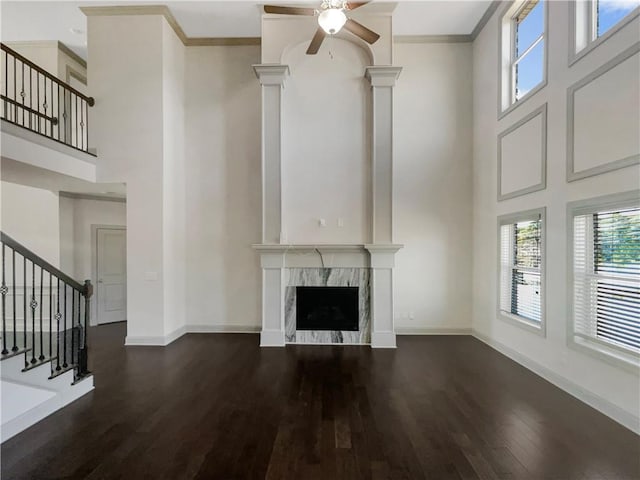 unfurnished living room with crown molding, dark wood-type flooring, baseboards, and a premium fireplace