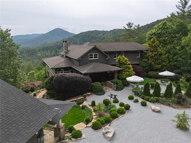 view of front of property with a chimney, a mountain view, a wooded view, and a patio