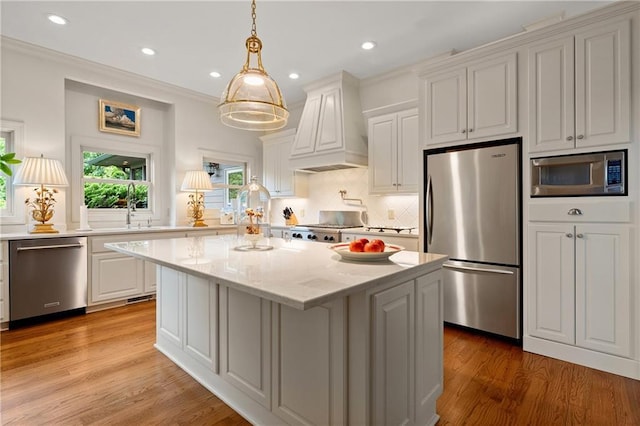 295 Goble Gap Ln, Clayton, GA 30525 - kitchen featuring appliances with stainless steel finishes, premium range hood, a kitchen island, light wood-type flooring, and white cabinets