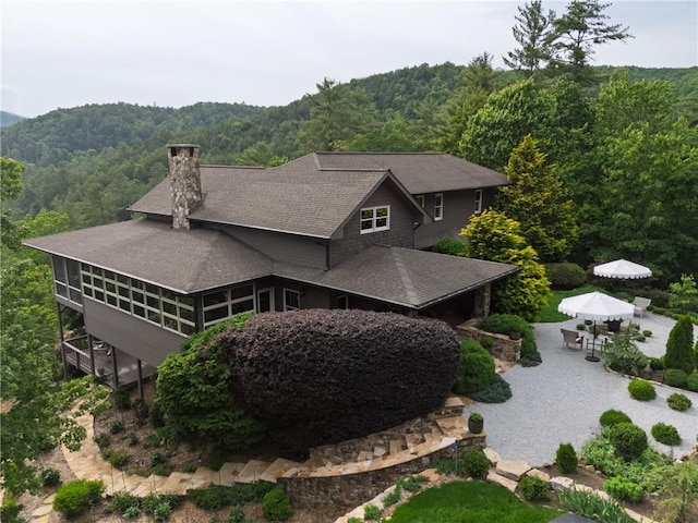 aerial view of property and surrounding area with a heavily wooded area and a mountainous background