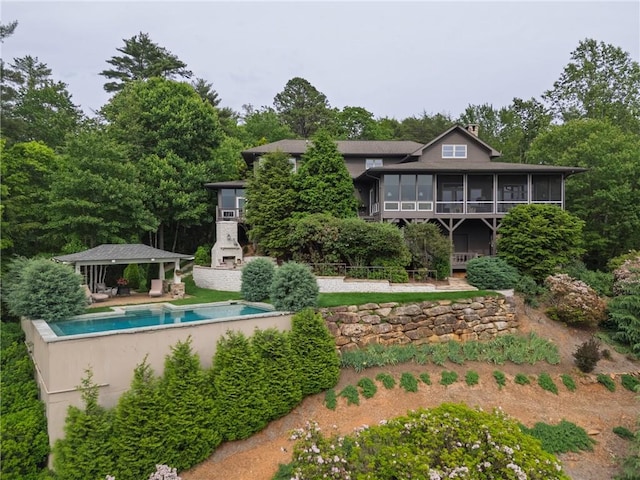 rear view of property featuring a sunroom and an outdoor pool