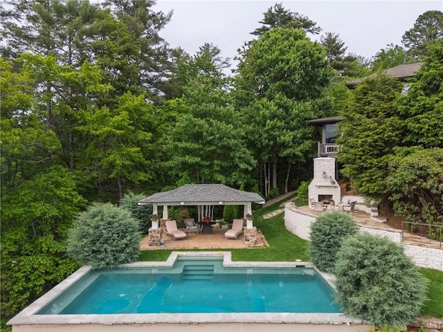 swimming pool featuring exterior fireplace, a patio, and a gazebo