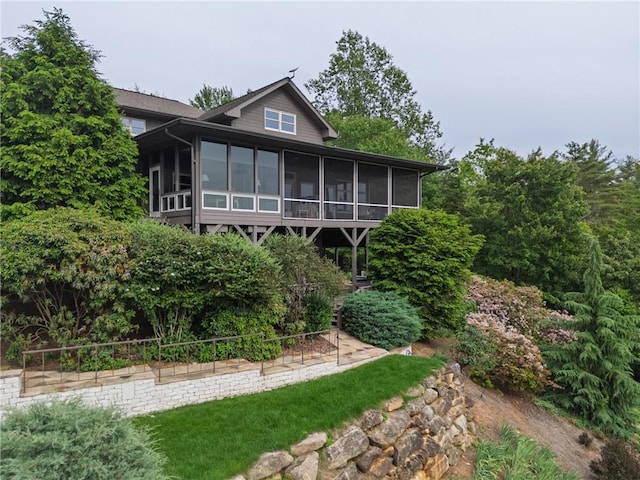 rear view of property with a sunroom and a garden