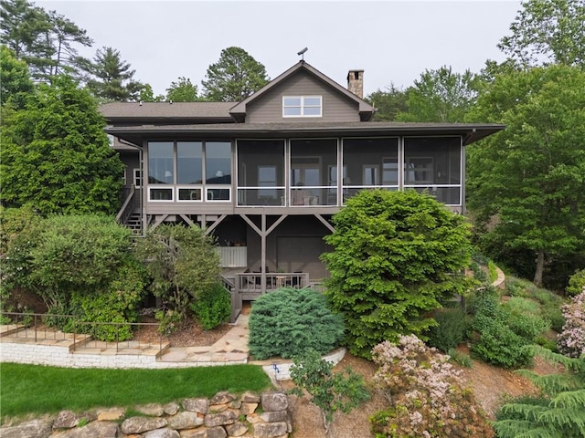 back of property featuring a sunroom and a chimney