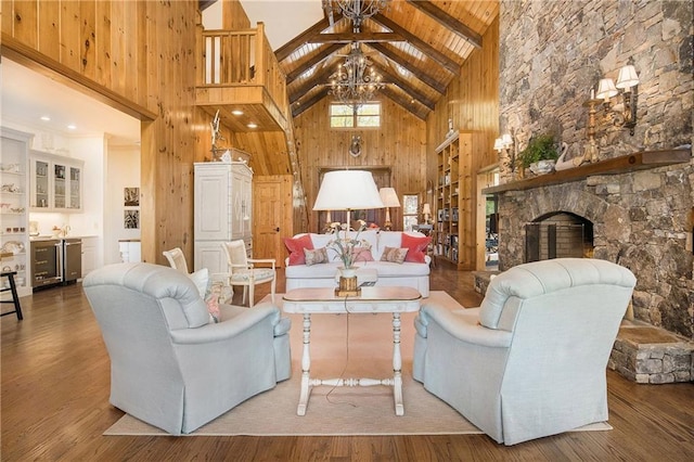 living room with high vaulted ceiling, a chandelier, beam ceiling, a fireplace, and wood finished floors