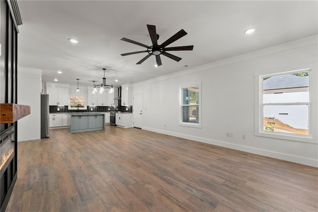 unfurnished living room featuring crown molding, ceiling fan, and wood-type flooring