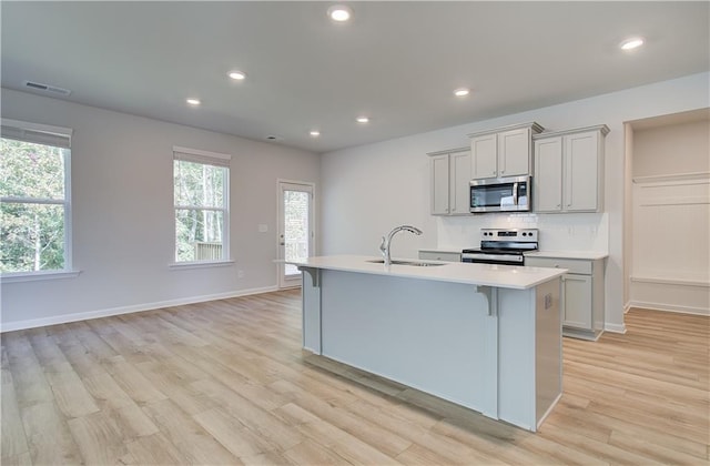 20 Fayme Ct, Newnan, GA 30263 - kitchen featuring appliances with stainless steel finishes, a sink, light countertops, a kitchen island with sink, and light wood finished floors