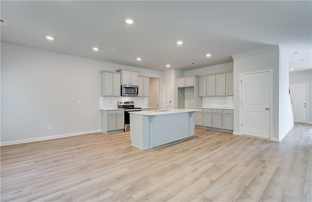 20 Fayme Ct, Newnan, GA 30263 - kitchen featuring stainless steel appliances, baseboards, gray cabinets, light wood-type flooring, and a kitchen island with sink