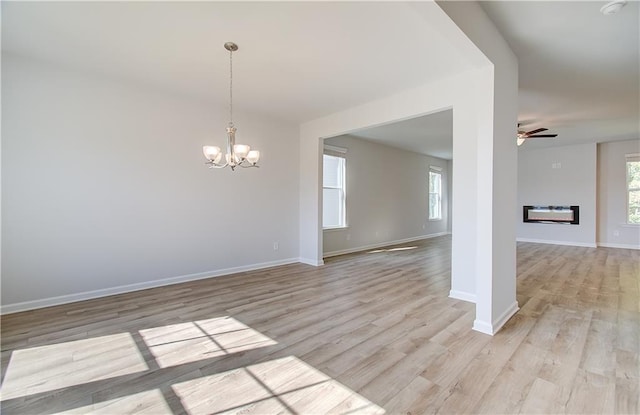 20 Fayme Ct, Newnan, GA 30263 - empty room featuring a chandelier, light wood finished floors, baseboards, ceiling fan, and a glass covered fireplace