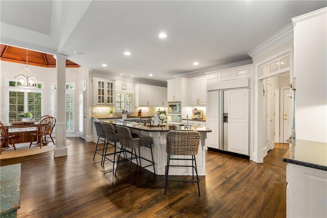 4789 Crest Park Ln, Marietta, GA 30068 - kitchen with built in appliances, ornamental molding, a kitchen bar, white cabinets, and dark wood finished floors
