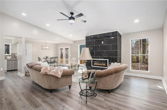 living area with baseboards, a ceiling fan, lofted ceiling, and wood finished floors