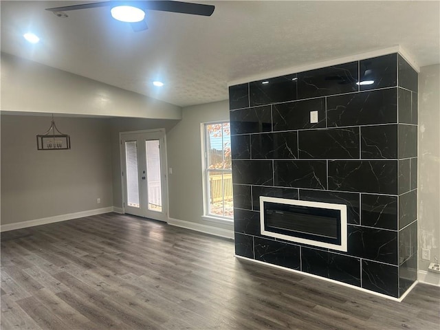 unfurnished living room with ceiling fan, french doors, hardwood / wood-style floors, lofted ceiling, and a fireplace