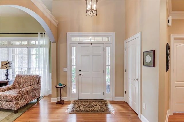 entryway with light wood-type flooring, baseboards, and crown molding