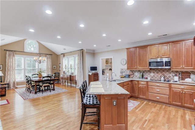 kitchen with a peninsula, a sink, visible vents, stainless steel microwave, and a kitchen bar