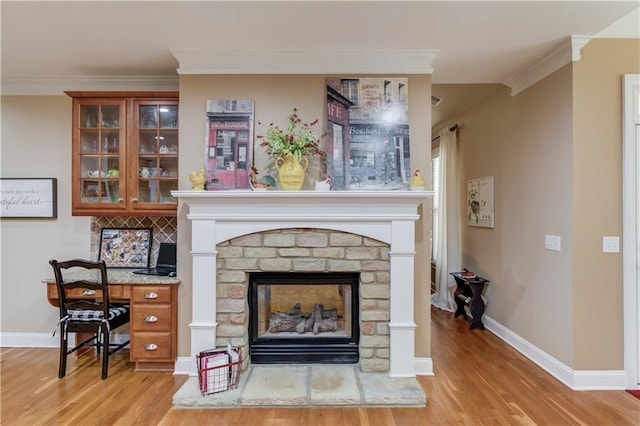 interior space featuring ornamental molding, a brick fireplace, baseboards, and light wood finished floors